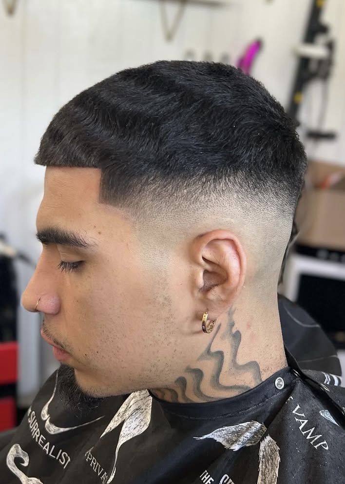 Low skin fade with textured top by Sharp Society Barbershop barber